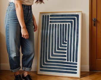 May include: A framed abstract art print featuring a geometric design of navy blue lines on a white background. The artwork is encased in a light wood frame and leans against a wall. The overall theme is modern home decor.