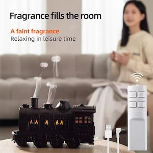 Könnte beinhalten: Schwarzer, zugförmiger Diffusor für ätherische Öle mit Fernbedienung. Der Diffusor hat einen Dampfeffekt und leuchtet mit orangefarbenen Flammen. Der Text "Fragrance fills the room" und "A faint fragrance Relaxing in leisure time" wird über dem Diffusor angezeigt.