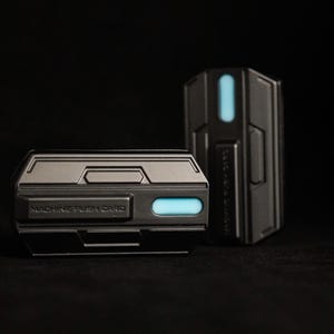 May include: Two black rectangular devices with a blue light. The smaller device has the text "MACHINE FLASH CARD" on it.
