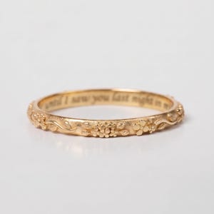 Puede incluir: Un anillo de oro con un delicado patrón floral y de enredaderas en relieve en su superficie exterior. El interior de la banda está grabado con el texto "until I saw you last night in my". El metal tiene un acabado mate suave en todo.