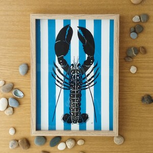 Bellissima linoleografia raffigurante un'aragosta nera su sfondo blu a strisce. Ideale come decorazione murale. Illustrazione firmata, stampa incisa a mano, incorniciata.