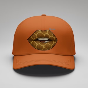 Könnte beinhalten: Orangefarbene Baseballkappe mit einem Giraffenmuster-Lippen-Grafik. Die Kappe hat einen gebogenen Schirm und eine strukturierte Krone. Das Wort "Dreams" ist hellblau auf der Kappe aufgedruckt.