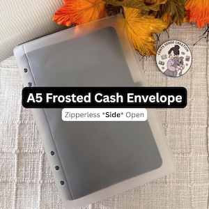 May include: A5 frosted cash envelope with a side opening. The clear, frosted envelope has a row of holes for binder use. The text "A5 Frosted Cash Envelope" and "Zipperless *Side* Open" are displayed on the image.