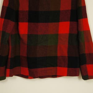 May include: A red, black, and green plaid jacket. The jacket has a classic lumberjack style with large, bold squares. The fabric appears to be a thick, warm material, suitable for colder weather. The jacket is displayed against a neutral background.