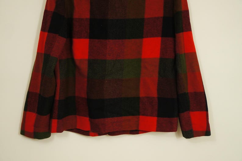 May include: A red, black, and green plaid jacket. The jacket has a classic lumberjack style with large, bold squares. The fabric appears to be a thick, warm material, suitable for colder weather. The jacket is displayed against a neutral background.