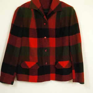 May include: A red, black, and green plaid jacket with a collared neckline and three red buttons. The jacket has two front pockets and is made of a thick, warm material.