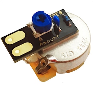 May include: Electronic component with a black circuit board, featuring two yellow rectangles and the word "Amount". A blue knob and other small blue components are visible. The component is attached to a silver-coloured circular piece.