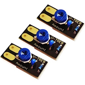 Puede incluir: Tres placas de circuito electrónico negras con componentes dorados y azules. Cada placa tiene una perilla azul con las etiquetas "Amount" y "U-TREB". Las placas están dispuestas en ángulo sobre un fondo blanco.