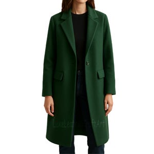 May include: A long, forest green coat with a classic lapel collar and two front pockets. The coat is buttoned and appears to be made of a wool or wool-blend material. The coat is knee-length.