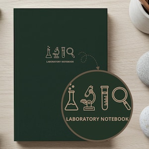 May include: A dark green laboratory notebook with a science-themed graphic and the words "LABORATORY NOTEBOOK". The notebook is on a light wood surface, with pencils and stones nearby.