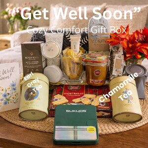 May include: A Get Well Soon gift box containing a Bondi Bliss mushroom powder box, a jar of honey, a box of shortbread, a Sukyos green device, and two cylindrical tins labeled Earl Gray Tea and Chamomile Tea, alongside a greeting card.