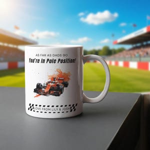 Puede incluir: Taza de cerámica blanca con un diseño de coche de carreras de Fórmula 1 y el texto "AS FAR AS DADS GO You're In Pole Position!" y "LOVE FROM LILY & JOSH". La taza tiene un asa curvada.