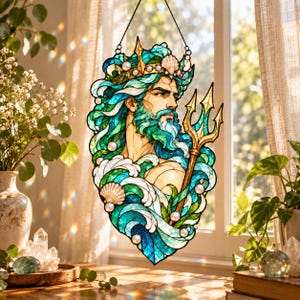 May include: A stained glass suncatcher depicting a bearded figure with a crown, holding a golden trident. The design features swirling teal, blue, and green waves, accented with white foam details and small round white pearls throughout the piece.