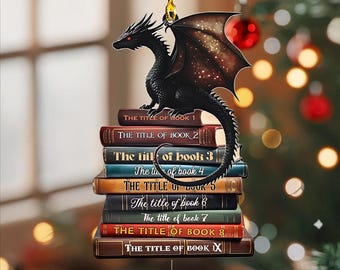May include: Black dragon ornament perched atop a stack of books. The books are labeled "The Title of Book 1" through "The Title of Book IX". The dragon has red eyes and detailed wings. A gold string is attached for hanging.