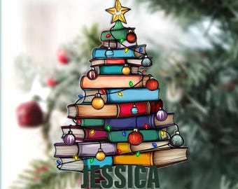 May include: A Christmas tree ornament shaped like a tree made of stacked books. The books are various colors and decorated with Christmas lights and ornaments. The name "JESSICA" is displayed at the bottom of the ornament. A gold star tops the tree.