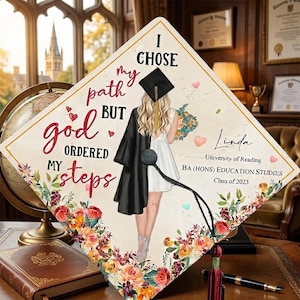 Op de afbeelding: Een afstudeerhoed met de tekst "I chose my path but God ordered my steps". De hoed heeft een afbeelding van een afgestudeerde en bloemmotieven. De hoed bevat ook de naam "Linda", de University of Reading en "Class of 2023".