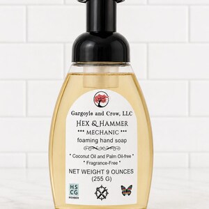 May include: A clear plastic bottle of foaming hand soap with a black pump dispenser. The label reads Gargoyle and Crow, LLC, HEX & HAMMER, MECHANIC, foaming hand soap, Coconut Oil and Palm Oil-free, Fragrance-Free, NET WEIGHT 9 OUNCES (255 G).