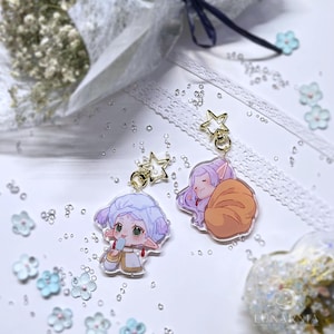 May include: Two acrylic charm keychains with anime-style characters and star-shaped gold hardware. One character has purple hair and is holding a popsicle. The other has purple hair and is curled up with a blanket. The background is white with floral accents.