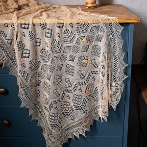 A beige silk lace shawl, draped over a blue drawer. Orange flower arrangement.