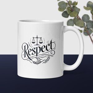 Witte glanzende mok met een woord van respect geschreven in een elegant lettertype met schalen van gerechtigheid, twee trillende handen en een olijfboomtak.