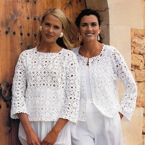 Peut inclure: Deux femmes portant des vestes en crochet blanc. Les vestes ont un motif floral et sont ouvertes à l'avant. Les femmes sont debout devant une porte en bois.