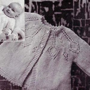 May include: A knitted baby cardigan with a button closure and a delicate lace pattern. The cardigan is light gray and has a scalloped edge.