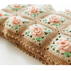 May include: A crocheted blanket with a brown and white pattern and pink and green flowers.
