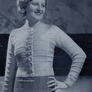 May include: A vintage black and white photo of a woman wearing a knitted cardigan with buttons down the front. The cardigan has a ribbed texture and a crew neckline.