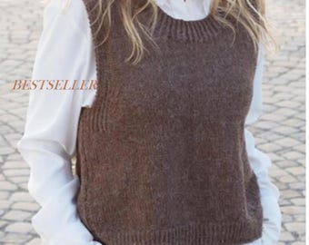 May include: A brown sleeveless knit sweater vest with a ribbed crew neckline and a ribbed hem, worn over a white long-sleeved collared shirt. The word BESTSELLER is printed in a light brown font on the left side of the brown knit sweater vest.