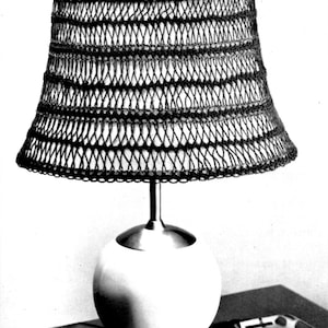May include: A black crocheted lampshade with a white globe base and three legs. The lampshade has a geometric pattern.