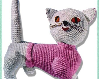 May include: A crocheted cat toy wearing a pink sweater. The cat has a white body with grey fur and orange eyes.