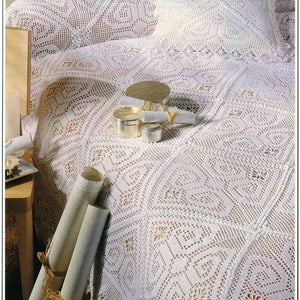 May include: A white crocheted throw blanket with a diamond pattern and a crocheted pillow. The blanket is on a couch with a wooden armrest.