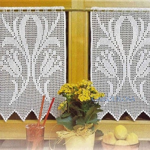 May include: Two white crocheted curtains with a floral design hang in a kitchen window. The curtains are made of a delicate, lacy material and have a scalloped edge. A potted plant with yellow flowers sits on the windowsill.