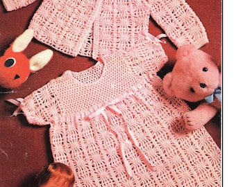 May include: A pink crocheted baby dress and matching cardigan. The dress has a tie at the waist and the cardigan has buttons down the front.