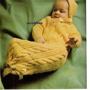 May include: A yellow knitted baby sleeping bag with a matching hat. The sleeping bag has a cable knit pattern and a ribbon tie at the neck.