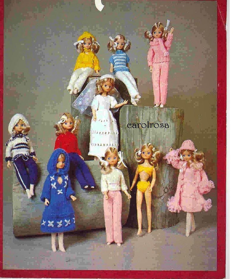 Op de afbeelding: Een verzameling vintage poppen gekleed in diverse outfits. De poppen dragen kleding in verschillende kleuren, waaronder geel, blauw, roze en wit. De tekst "carolrosa" is zichtbaar.