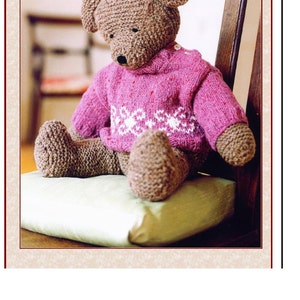 May include: A brown knitted teddy bear wearing a pink knitted sweater with a white snowflake pattern sits on a green cushion. The teddy bear is sitting on a wooden chair. The text "Need A Hug Real Bad Teddy!" is at the top of the image.