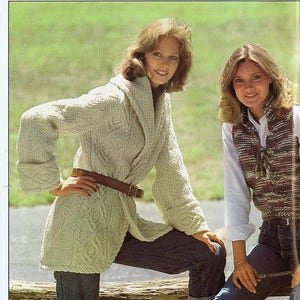 以下が含まれることがあります： セーターとジーンズを着用した2人の女性。左側の女性は、茶色のベルトが付いた白いニットカーディガンを着ています。右側の女性は、白いシャツと茶色と白の模様のベストを着ています。