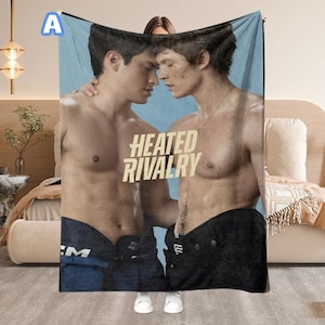 May include: A blanket featuring two shirtless men with the text "HEATED RIVALRY" in a bold font. The blanket has a light blue background and the men are wearing dark blue and black hockey pants.