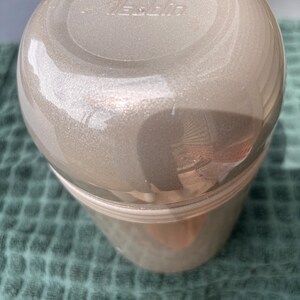 May include: A silver-colored thermos with a white lid and the word "Thermos" printed on the lid.