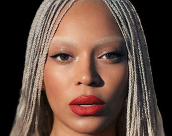 May include: A portrait of a person with light skin, platinum blonde braids, and bold red lipstick. The image features the text "BEYONCÉ" at the top left and "COWBOY CARTER TOUR" at the top right, set against a black background.