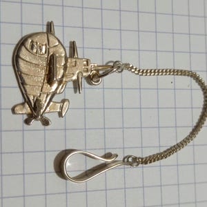 May include: A gold-coloured charm of a small aeroplane with a chain attached. The chain has a clasp.