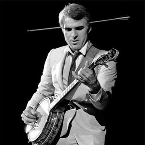 Könnte beinhalten: Ein Mann im Anzug spielt Banjo. Er trägt eine Krawatte und hat ein Mikrofon vor sich.