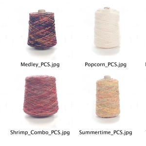 May include: Eight spools of yarn in various colors and patterns, including blue, grey, red, tan, and white. The yarn is arranged in two rows of four spools each.