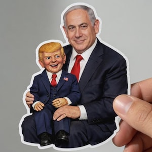 Puede incluir: Una pegatina que muestra a un hombre con un traje oscuro y corbata roja sosteniendo una figura más pequeña con un traje azul y corbata roja. La figura más pequeña tiene el pelo rubio. La pegatina está sujeta por una mano.