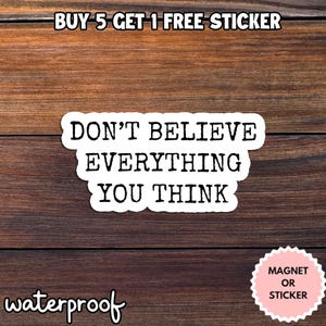 May include: A white sticker with the text "DON'T BELIEVE EVERYTHING YOU THINK" in a bold, black font. The sticker is on a wooden background. The word "waterproof" is written in a cursive font. A pink sticker that says "MAGNET OR STICKER" is also visible.