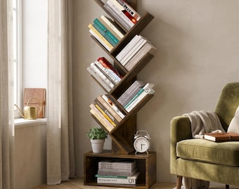 May include: A tall, dark brown wooden tree-shaped bookshelf with multiple angled shelves holding various books. The unit features a rectangular base compartment containing stacked books and a silver analog alarm clock on the top surface.