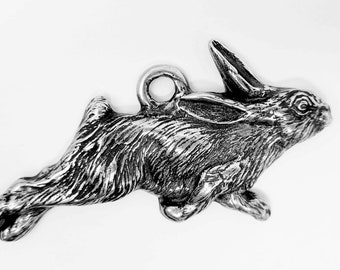 May include: A silver charm in the shape of a rabbit jumping. The rabbit is detailed with fur and has a loop at the top for attaching to a bracelet or necklace.