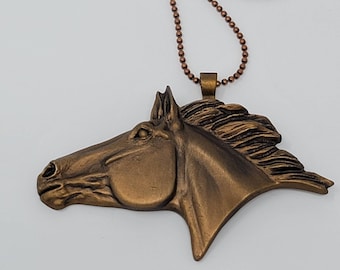 May include: A gold-toned horse head pendant necklace with a copper chain.