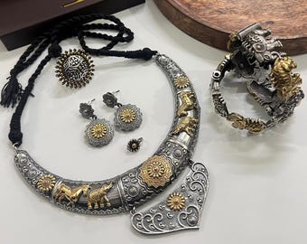 Puede incluir: Un conjunto de joyas ornamentado con un collar, pendientes, un anillo y una pulsera de plata y oro. El collar tiene forma de media luna con diseños de animales y flores. Los pendientes y el anillo tienen un diseño de sol. La pulsera tiene un diseño detallado de animales.
